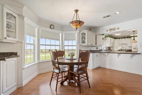 a large white kitchen with kitchen island a stove a sink wooden floor and a window
