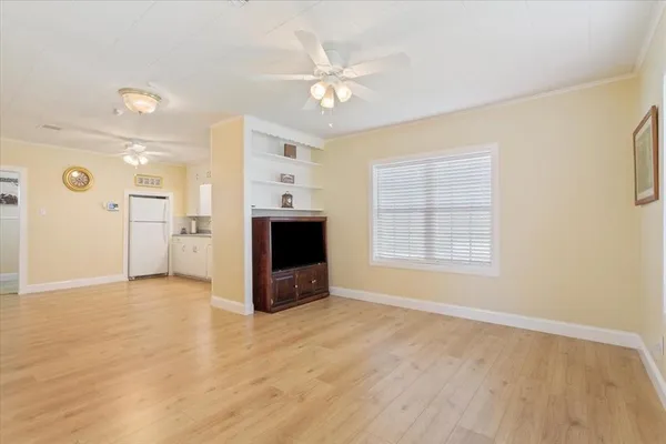 a view of an empty room with a window and wooden floor