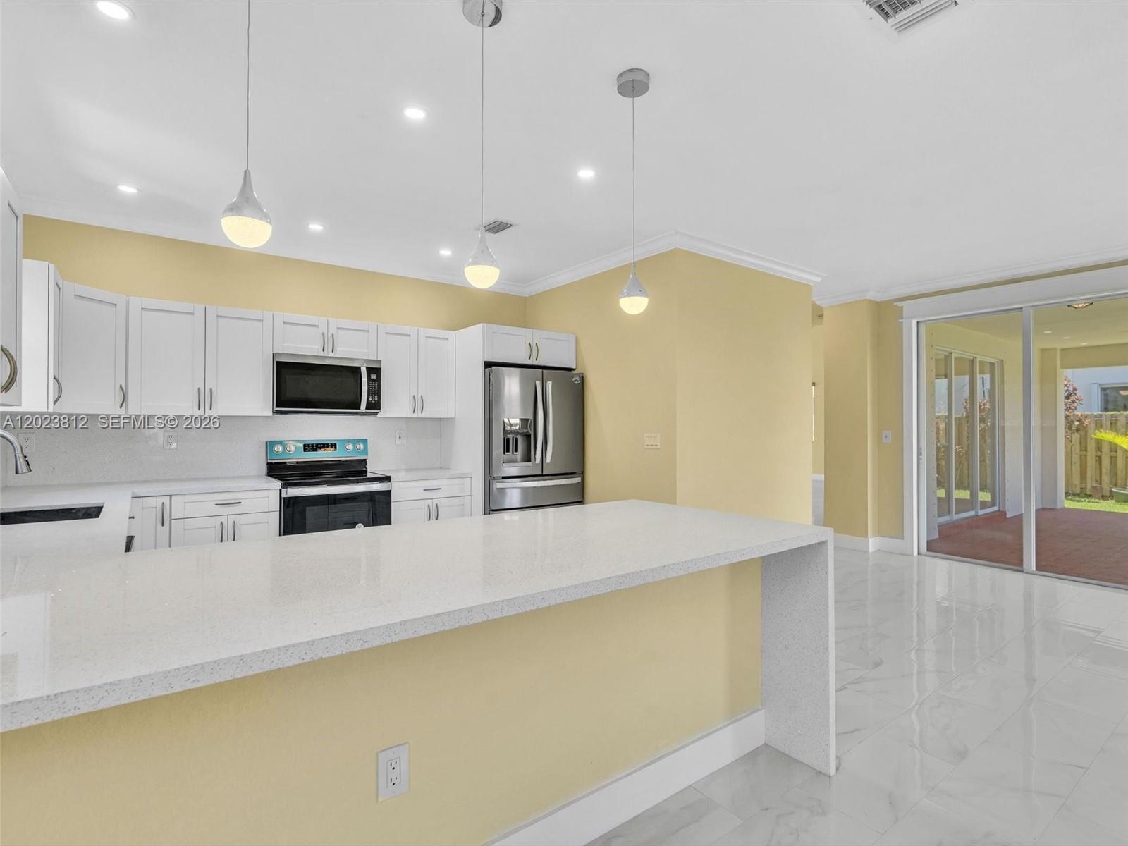 2864 Southwest 138th Path Miami, FL 33175 - Photo 15 of 40 a large kitchen with stainless steel appliances a large counter top a stove a refrigerator a sink a microwave and a refrigerator