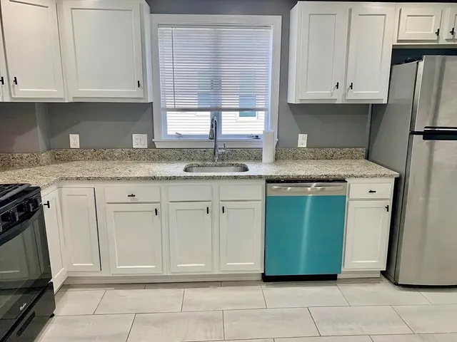 a kitchen with granite countertop a sink and a refrigerator