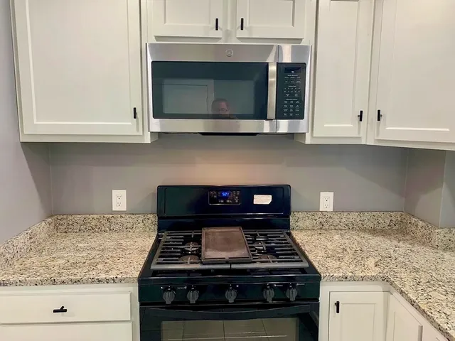 a kitchen with granite countertop white cabinets and appliances