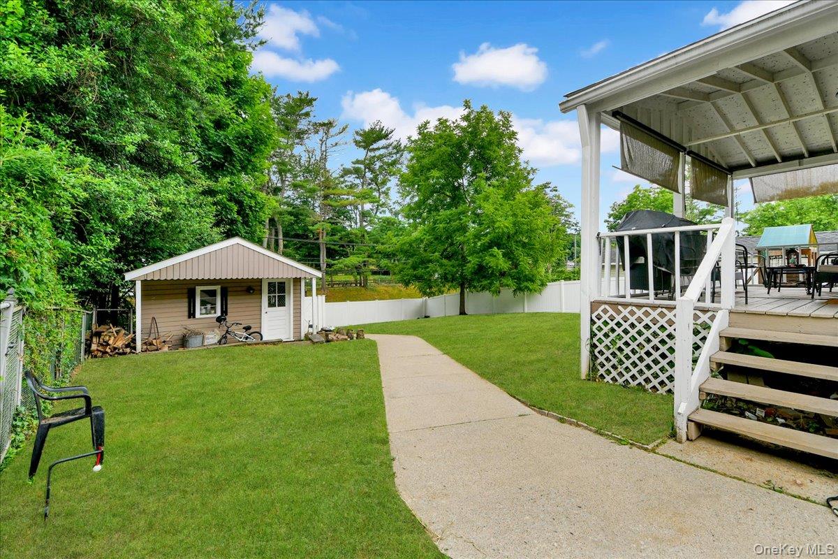 10 Susquehanna Road Ossining, NY 10562 - Photo 22 of 31 Expansive backyard featuring a covered patio, a detached storage shed, a concrete pathway, a chain-link fence, and a white privacy fence