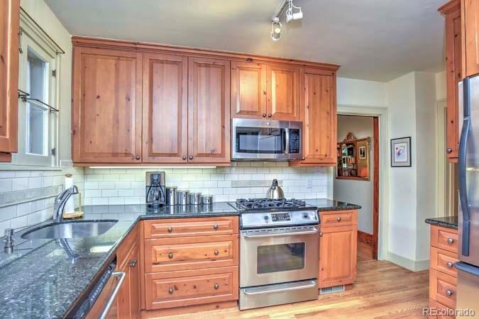 2536 Glencoe Street Denver, CO 80207 - Photo 7 of 26 a kitchen with granite countertop wooden cabinets and stainless steel appliances