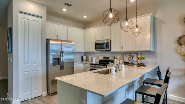a kitchen with stainless steel appliances granite countertop a sink a stove a refrigerator cabinets and chairs