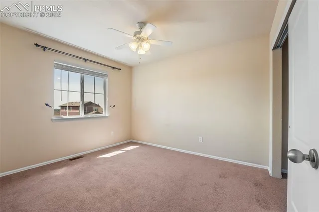 an empty room with windows and chandelier fan
