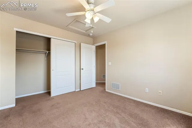 an empty room with a chandelier fan and windows