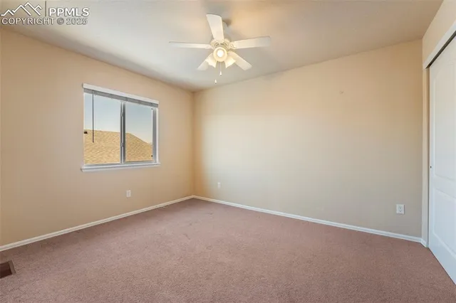 an empty room with a window and a fan
