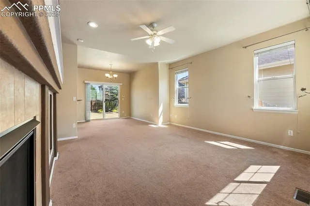 an empty room with windows and ceiling fan