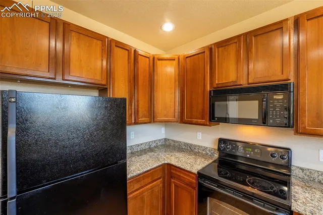 a kitchen with granite countertop wooden cabinets and a stove top oven