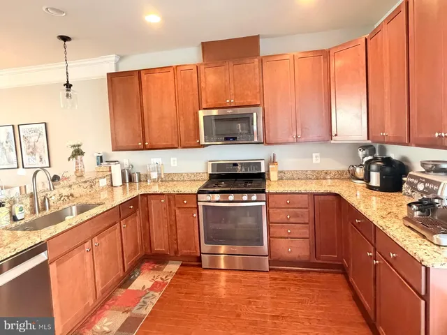 a kitchen with stainless steel appliances granite countertop a stove a sink dishwasher and a microwave oven with cabinets