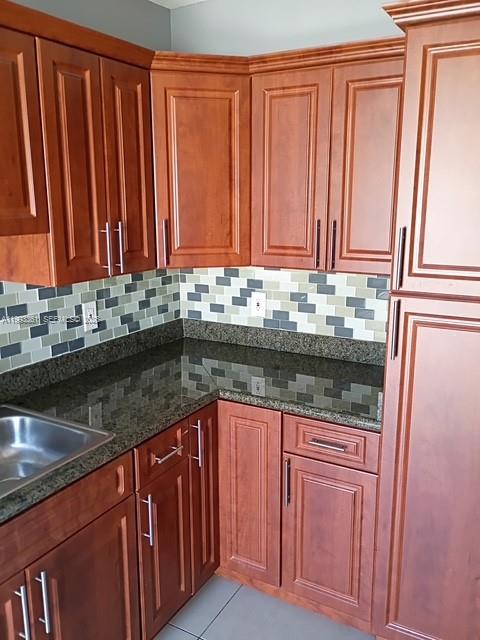 755 83rd Street, Unit 3 Miami Beach, FL 33141 - Photo 15 of 24 a kitchen with granite countertop wooden cabinets a sink and a dishwasher
