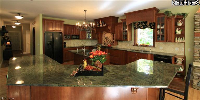 7900 Bainbridge Road Bainbridge, OH 44023 - Photo 8 of 25 For professional and aspiring chefs alike, and for all who desire a luxury cooking environment, you'll love the custom oversized Gourmet Kitchen! It has cherry cabinets, several of which have glass doors, black built-in appliances, Hickory floors, and gorgeous granite countertops that provide an abundance of useful work space. There is a combination center island breakfast bar with prep sink and a Maytag dishwasher, a huge breakfast bar with double side-by-side KitchenAid ovens, a custom hand-painted limest
