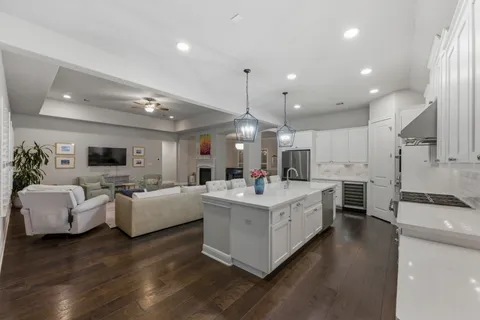 a large kitchen with a counter space a sink appliances and living room view
