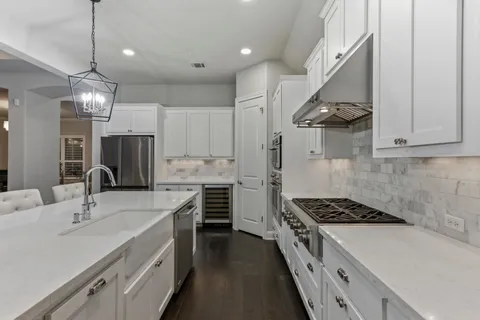 a large white kitchen with a large window and white cabinets