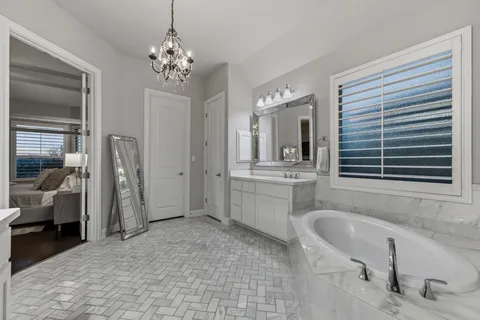a spacious en suite bathroom with a granite countertop sink mirror and bathtub