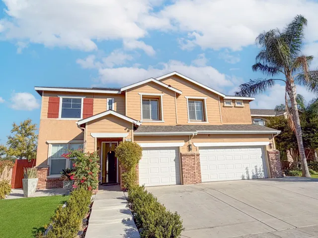 a front view of a house with a garden and trees