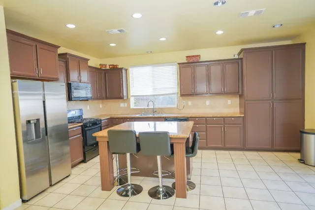 a kitchen with stainless steel appliances granite countertop a refrigerator and a stove top oven
