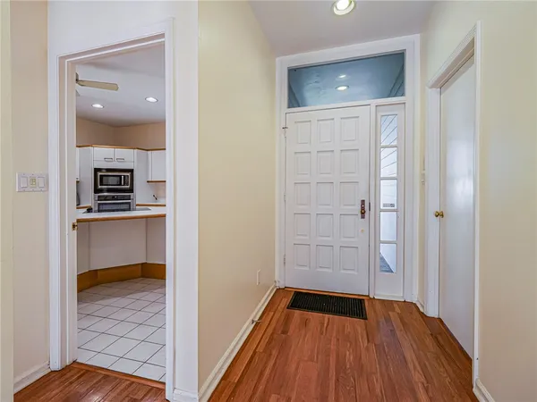 a view of an empty room with wooden floor a ceiling fan and windows