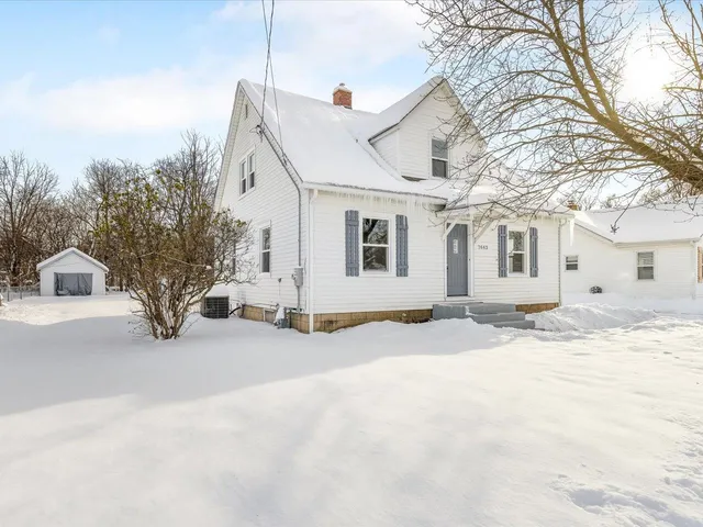 a view of a white house with a yard covered in snow