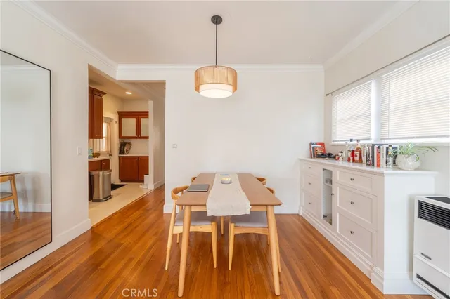 a dining room with wooden floor a chandelier a wooden table and chairs