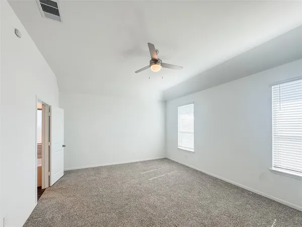 an empty room with windows and ceiling fan