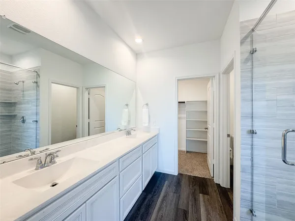 a spacious bathroom with a double vanity sink a mirror and a shower