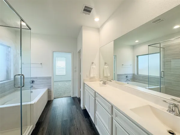a spacious bathroom with a tub sink shower and mirror