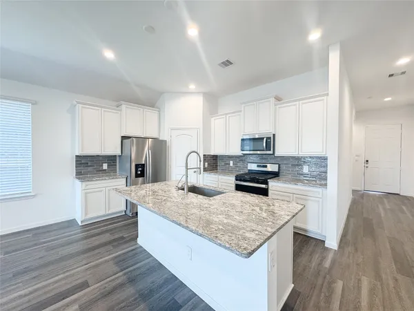 a kitchen with a stove a sink a microwave a refrigerator and cabinets