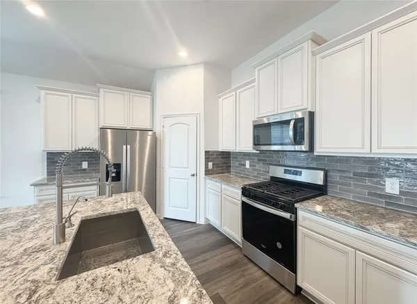 a kitchen with granite countertop a refrigerator stove and microwave