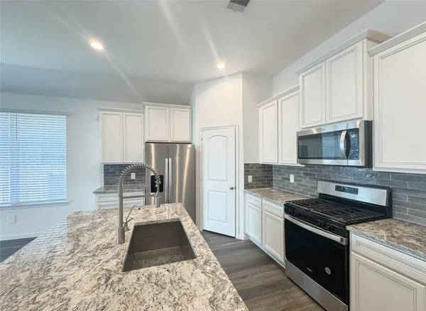 a kitchen with granite countertop stainless steel appliances a stove refrigerator and cabinets