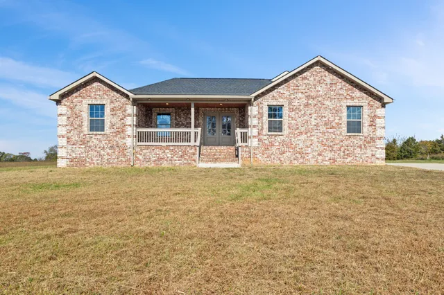 a front view of house with yard and trees in the background