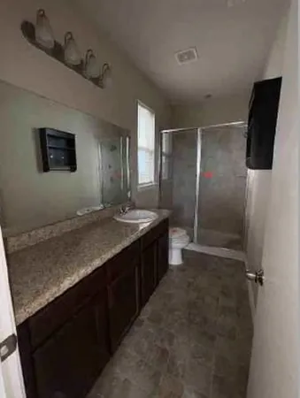 a bathroom with a granite countertop sink a toilet a mirror and vanity