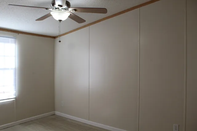 an empty room with a window and a chandelier fan