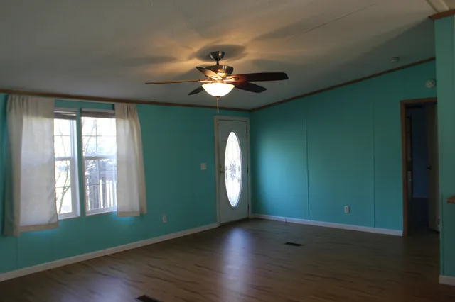 a view of an empty room with window and wooden floor