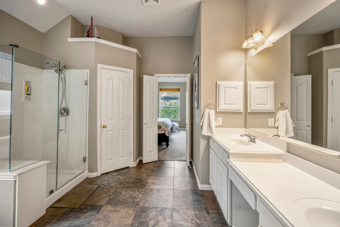 6811 PInehearth Court Spring, TX 77379 - Photo 22 of 50 From this angle, the primary bath highlights the upgraded walk-in shower with glass enclosure, along with an extended dual-sink vanity and dedicated seated vanity space. The private water closet sits just beyond, topped with a decorative display ledge that adds a subtle architectural touch.