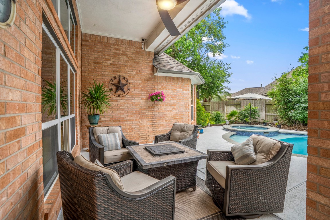 6811 PInehearth Court Spring, TX 77379 - Photo 29 of 50 Stepping outside, the covered patio creates an easy extension of the living space—complete with a ceiling fan overhead and plenty of room to relax or gather. Just beyond, the pool and spa invite you to unwind, whether it’s a quiet morning coffee or an evening spent enjoying the water. With a thoughtfully designed layout and low-maintenance surroundings, this backyard is set up for both everyday enjoyment and effortless entertaining.