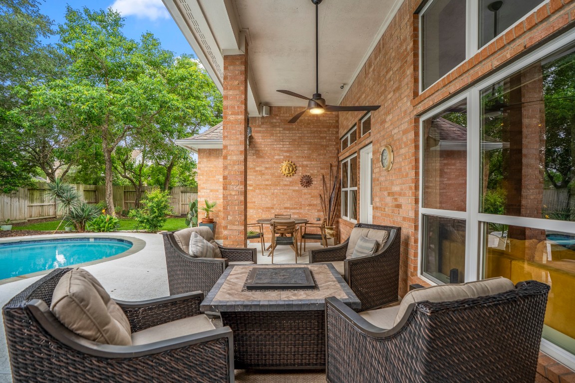 6811 PInehearth Court Spring, TX 77379 - Photo 30 of 50 From this angle, the full depth of the covered patio comes into view—offering multiple seating areas beneath the shade of the overhead ceiling fan, with easy access to the pool and spa just steps away. It’s a space that naturally lends itself to slow mornings, relaxed evenings, and gathering with friends while staying connected to the outdoors.