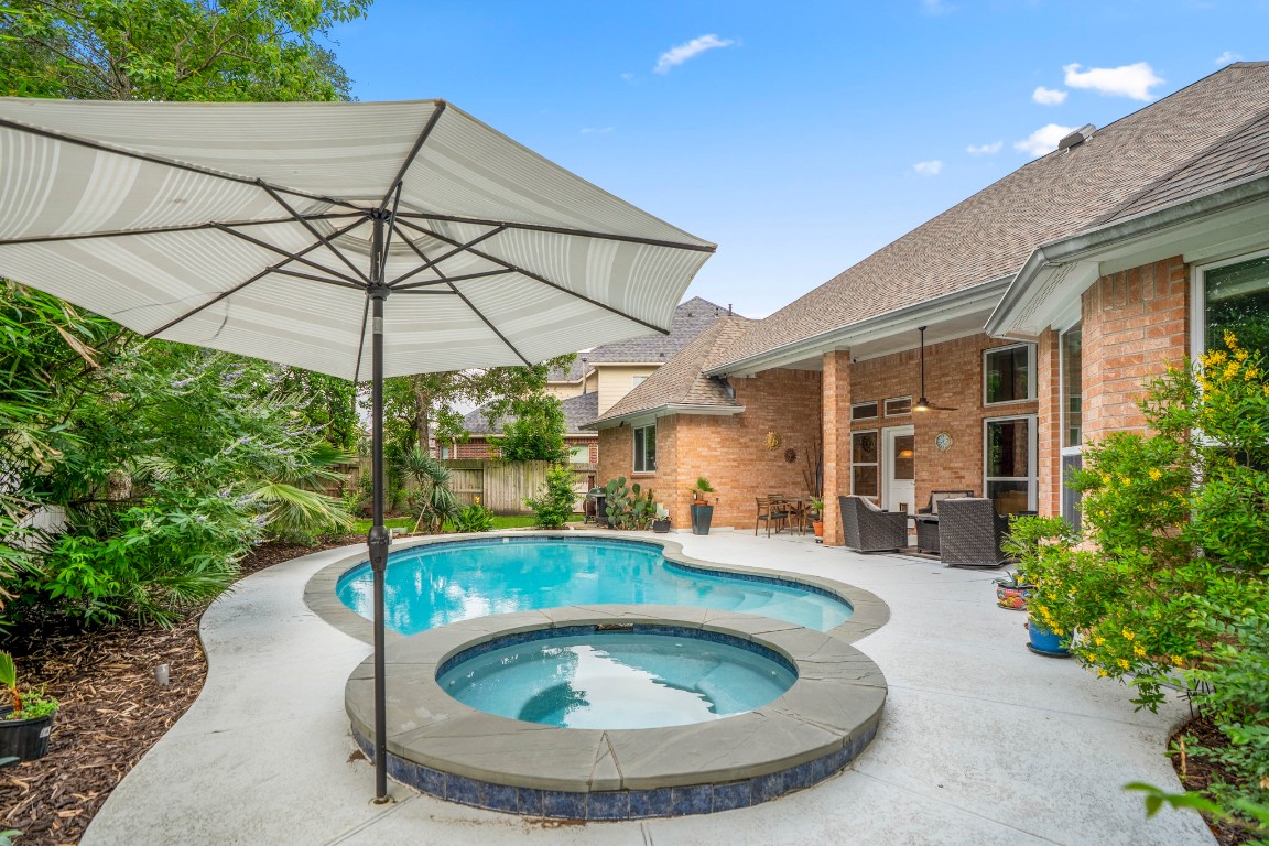 6811 PInehearth Court Spring, TX 77379 - Photo 32 of 50 A closer look at the pool and spa highlights the inviting layout—smooth curves, updated decking, and plenty of space to lounge or gather poolside. Just beyond, the covered patio creates an easy transition between shaded seating and open-air enjoyment, making it just as suited for quiet evenings as it is for hosting.