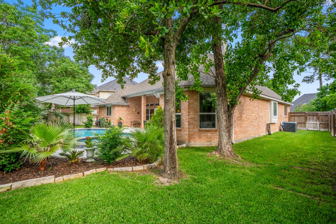 6811 PInehearth Court Spring, TX 77379 - Photo 33 of 50 Stepping out into the grass beyond the pool, the yard opens up to even more usable space—shaded by mature trees and framed by established landscaping. From here, you can see how the lawn, pool, and patio all connect, creating a setting that feels both private and easy to enjoy day to day.