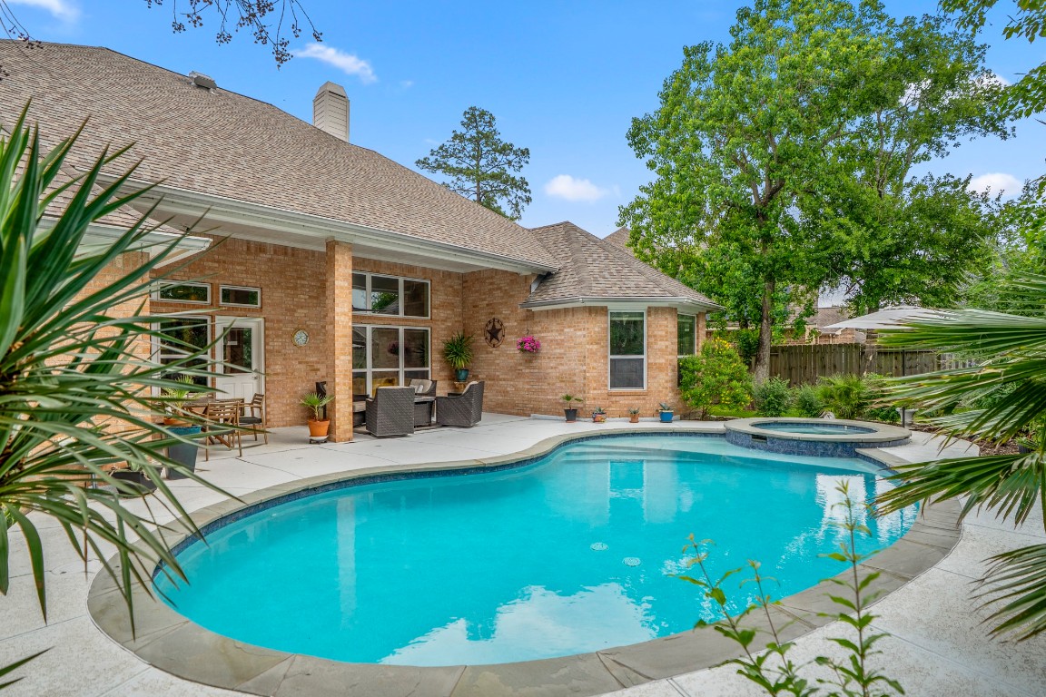 6811 PInehearth Court Spring, TX 77379 - Photo 35 of 50 A closer look at the pool and spa highlights the curved design and inviting layout, with refreshed surfacing, updated coping, and improved equipment already in place. Surrounded by greenery and just steps from the covered patio, it’s a space designed for easy outdoor living from day one.