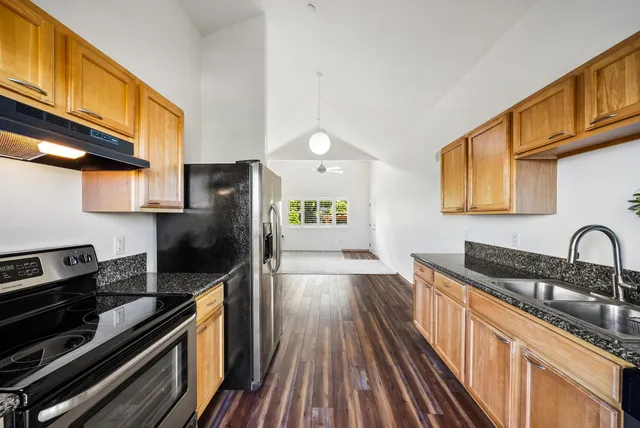 a kitchen with stainless steel appliances granite countertop a refrigerator a stove and a wooden floors