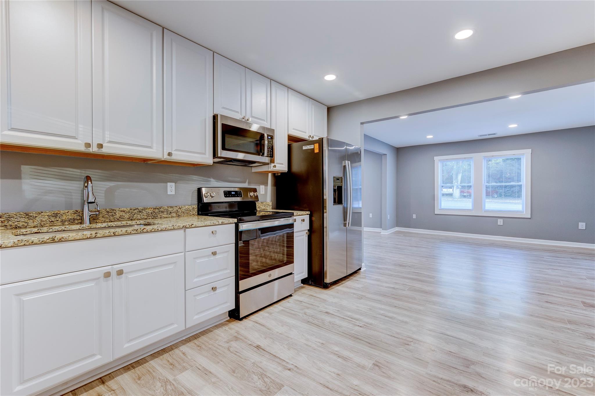 4641 Fallston Road Lawndale, NC 28090 - Photo 17 of 38 a kitchen with granite countertop a stove top oven a sink dishwasher and a refrigerator with wooden floor