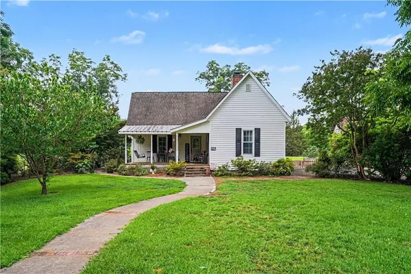 a front view of a house with a garden and trees