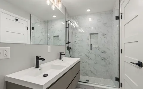 a bathroom with a sink shower and a mirror