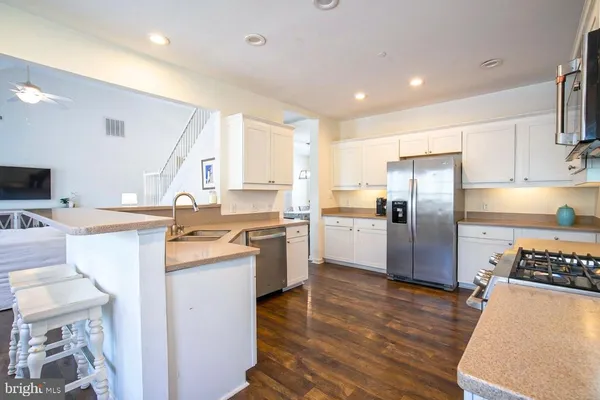 a kitchen with a sink a refrigerator and wooden floor