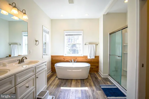 a spacious bathroom with sink a mirror a bathtub and shower