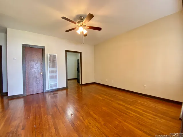 a view of an empty room with wooden floor and a window