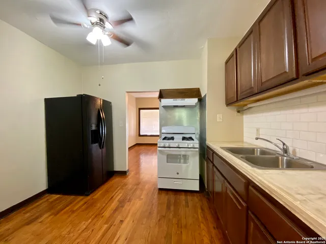 a kitchen with stainless steel appliances granite countertop a refrigerator a sink dishwasher and wooden cabinets with wooden floor