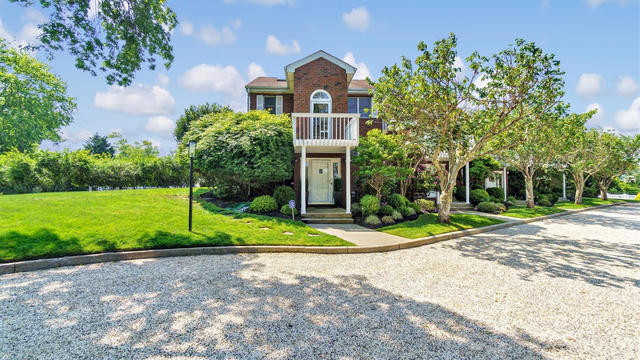 a view of a house with a big yard plants and large trees