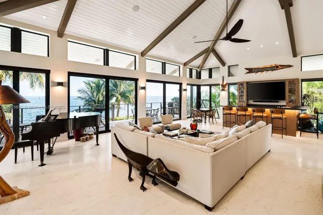 a living room with furniture a flat screen tv and floor to ceiling window